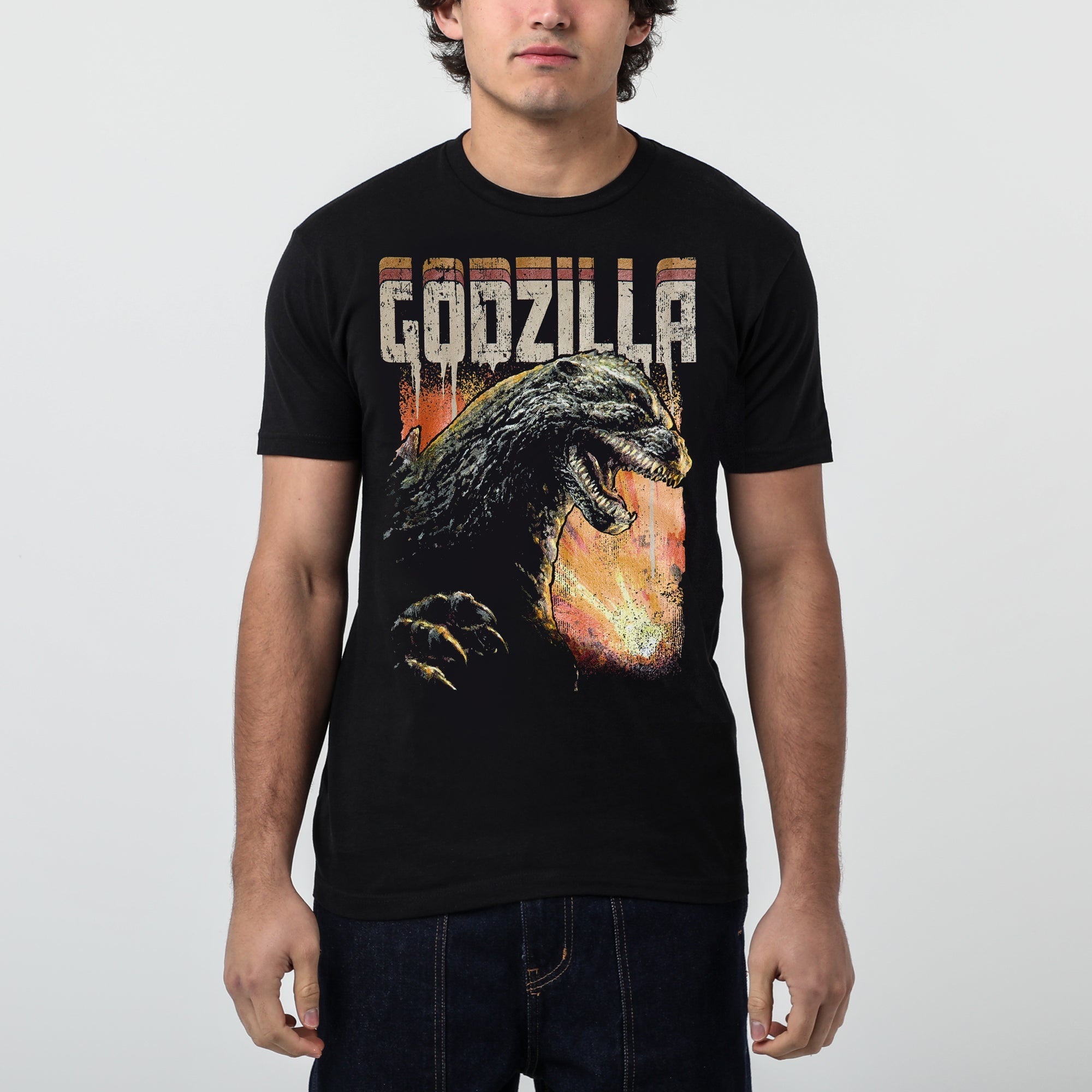 Male modeling Black T-shirt featuring a roaring Godzilla with a fiery background and distressed "Godzilla" text.